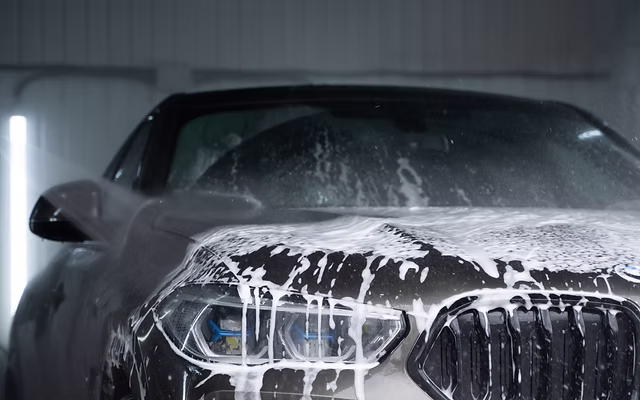 Mobile detailer carefully hand washing a vehicle with premium soap and water
